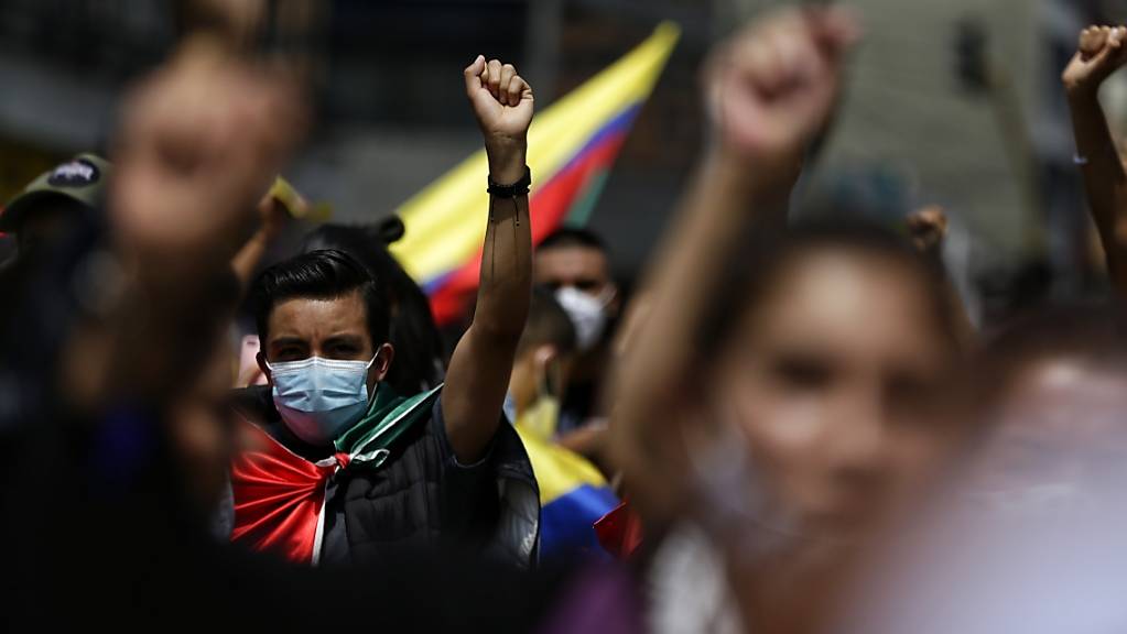 Demonstranten mit Mund-Nasen-Bedeckung ballen die Faust während einer Kundgebung am siebten Tag der Proteste gegen die Regierung inmitten der Corona-Pandemie. Nach tagelangen Protesten gelten mehr als 370 Menschen als vermisst. Foto: Sergio Acero/colprensa/dpa