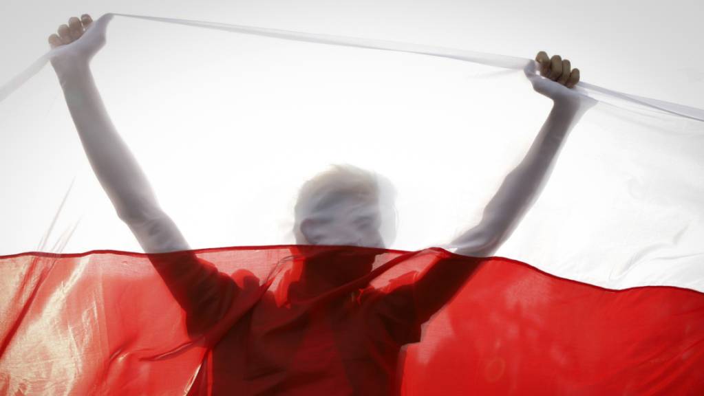 ARCHIV - Ein Demonstrant hält eine historische belarussische Fahne. Trotz eines Grossaufgebots an Sicherheitskräften haben Zehntausende Menschen gegen den autoritären Staatschef Lukaschenko demonstriert. Foto: Uncredited/AP/dpa