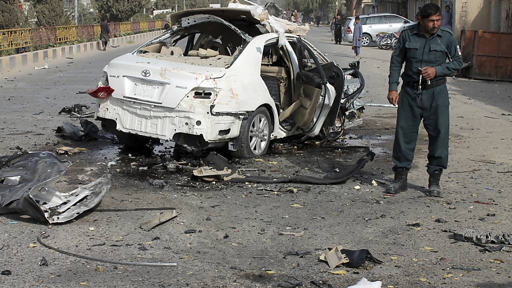 Ein Polizist untersucht ein beschädigtes Auto nach einem Bombenanschlag in der südafghanischen Provinz Helmand. Eine Bombe am Fahrzeug eines Journalisten explodierte am Donnerstag und tötete ihn. Mindestens zwei weitere Menschen, darunter der Bruder des Opfers, seien verwundet worden. Foto: Abdul Khaliq/AP/dpa