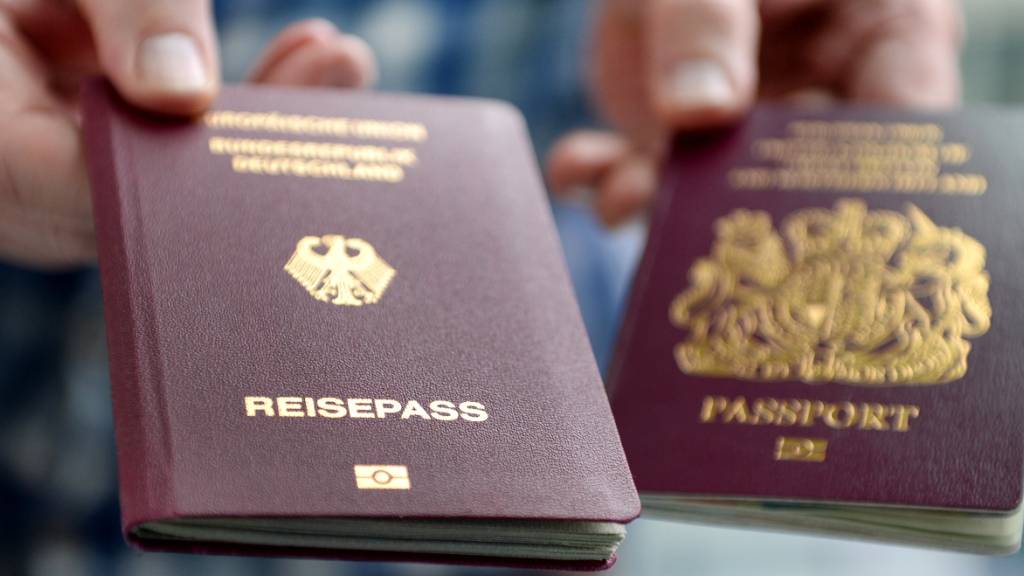 ARCHIV - Ein britischer und ein deutscher Reisepass werden in die Kamera gehalten. Der Brexit und die Corona-Pandemie haben die Zahl der Neubürger in Deutschland schrumpfen lassen. Foto: Britta Pedersen/zb/dpa