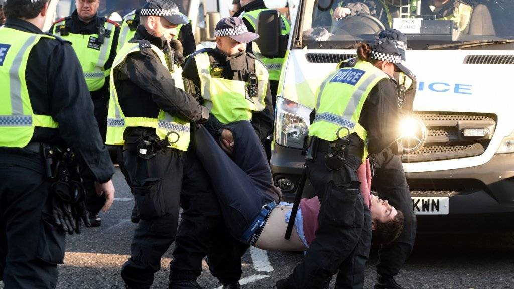 Ein Demonstrant wird von der Polizei von der Lambeth Bridge weggetragen.