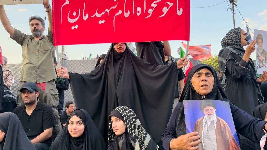 Trauernde halten Schilder und Porträts des ermordeten iranischen Obersten Führer Ajatollah Ali Chamenei hoch, während sie auf dem Platz der Islamischen Revolution auf seinen Trauerzug in Teheran, Iran, warten. Foto: Altaf Qadri/AP/dpa