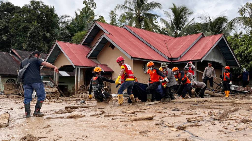 Rettungskräfte tragen die Leiche eines Flutopfers. Foto: Ade Yuandha/AP/dpa