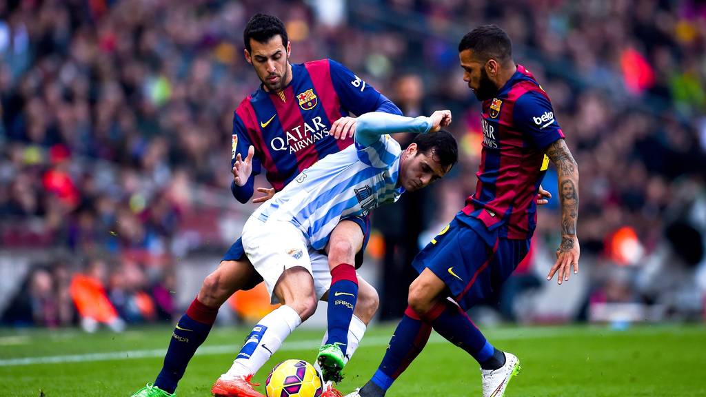 BARCELONA, SPAIN - FEBRUARY 21:  Juanmi Jimenez of Malaga CF competes for the ball with Sergio Busquets and Dani Alves of FC Barcelona during the La Liga match between FC Barcelona and Malaga CF at Camp Nou on February 21, 2015 in Barcelona, Spain.  (Photo by David Ramos/Getty Images)