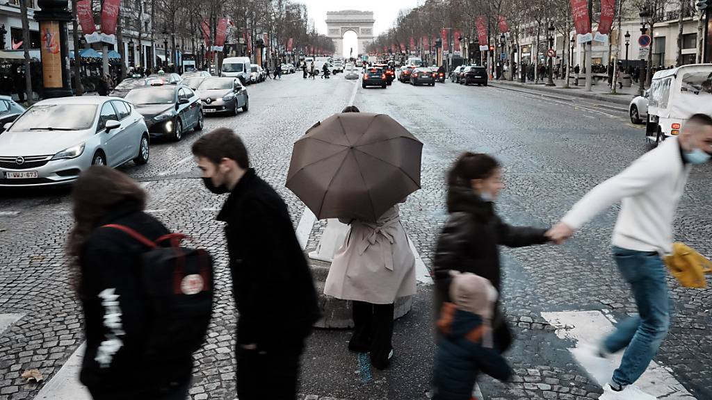 Menschen überqueren die Avenue des Champs-Elysees. Foto: Thibault Camus/AP/dpa