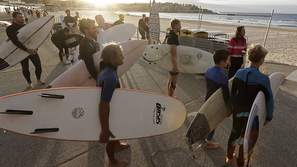 Surferinnen und Surfer warten auf die Öffnung des Bondi Beach in Sydney. Dort darf wieder Sport getrieben werden.
