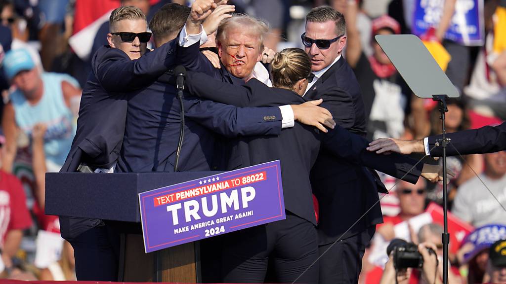 Agenten des US-Geheimdienstes Secret Service schützen den republikanischen Präsidentschaftsbewerber und ehemaligen US-Präsidenten Donald Trump auf der Bühne bei einer Wahlkampfveranstaltung in Butler, Pennsylvania. Foto: Gene J. Puskar/AP/dpa