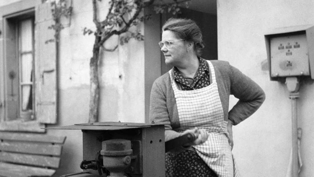 Eine Bahnwärterin betätigt im Jahr 1953 die Kurbel am Bahnübergang bei Faoug im Kanton Waadt, um manuell die Barriere am bewachten Bahnübergang zu schliessen.