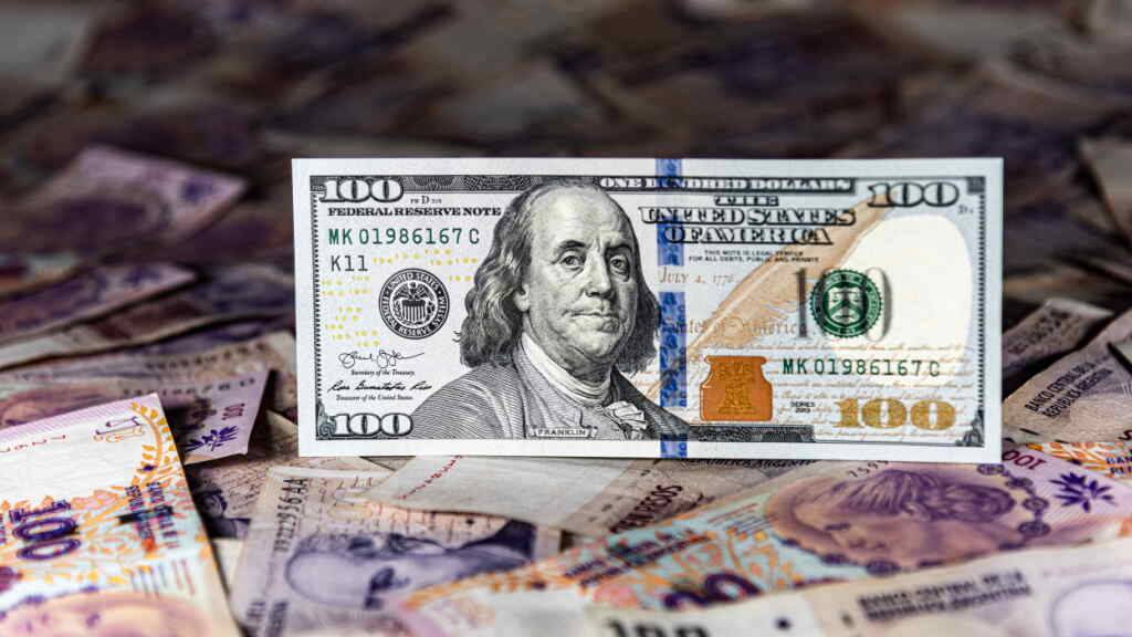 SYMBOLBILD - Ein 100-US-Dollar-Schein steht über zahlreichen Scheine des argentinischen Peso. Foto: Maximiliano Ramos/Zuma Press/dpa