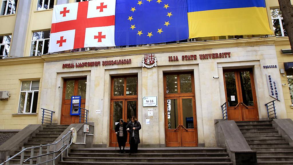 Die Flaggen von Georgien (l-r), der EU und der Ukraine hängen während der Parlamentswahlen in Georgien an der Außenwand eines Wahllokals in Tiflis. Foto: Shakh Aivazov/AP/dpa