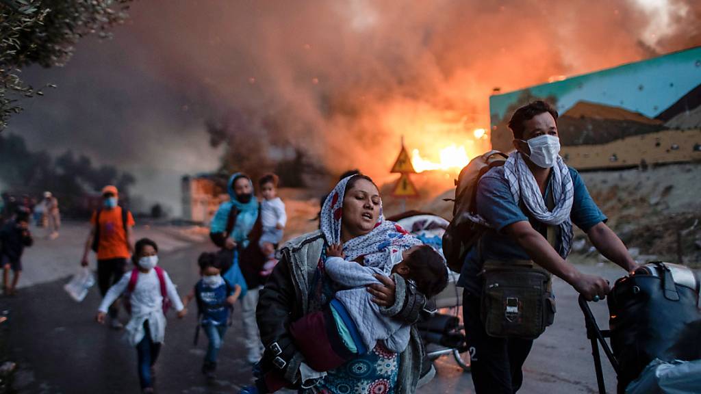 ARCHIV - Migranten fliehen vor einem erneuten Feuers mit ihren Habseligkeiten aus dem Flüchtlingslager Moria. Foto: Petros Giannakouris/AP/dpa