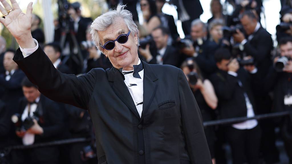ARCHIV - Wim Wenders winkt bei der Ankunft zur Preisverleihung während der 77. Internationalen Filmfestspiele. Der Regisseur aus Deutschland wird mit dem Großen Deutsch-Französischen Journalistenpreis für sein Lebenswerk geehrt. Foto: Vianney Le Caer/Invision/AP/dpa