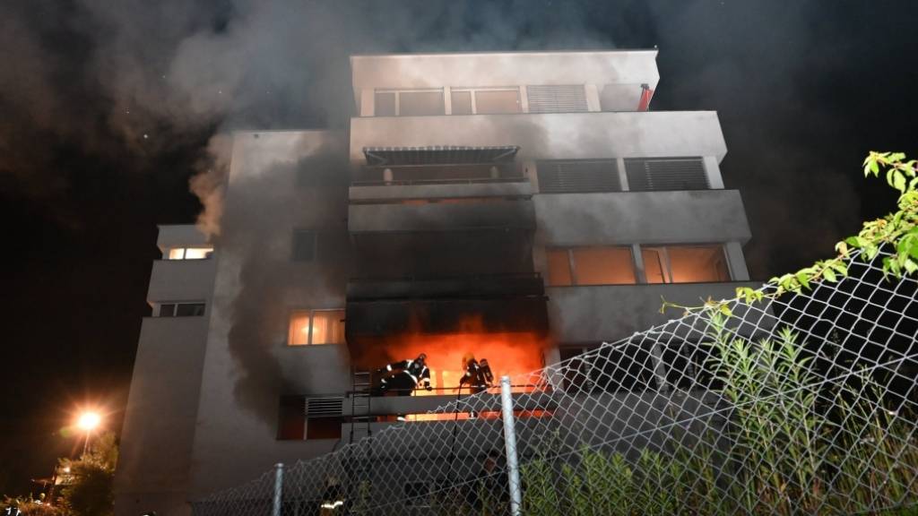Feuerwehrleute bekämpfen vom Balkon aus den Wohnungsbrand in Murg SG.