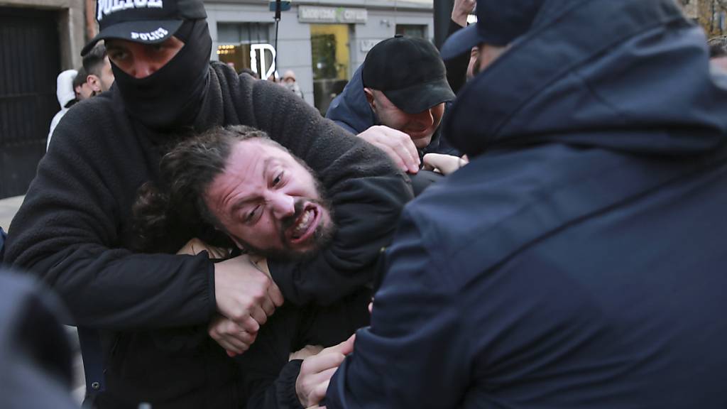 dpatopbilder - Die Polizei versucht, einen Demonstranten während einer Kundgebung gegen die Ergebnisse der Parlamentswahlen in Tiflis auf der Straße festzuhalten. Foto: Zurab Tsertsvadze/AP/dpa