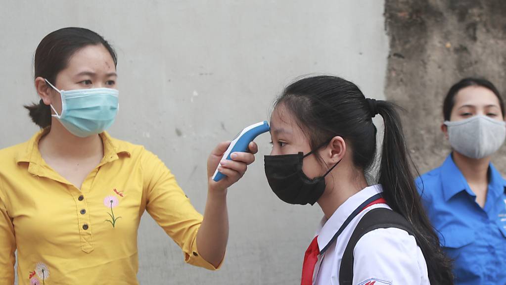 ARCHIV - Das Archivfoto aus dem Mai zeigt eine Fiebermessung bei einer Schülerin in Hanoi. Foto: Hau Dinh/AP/dpa