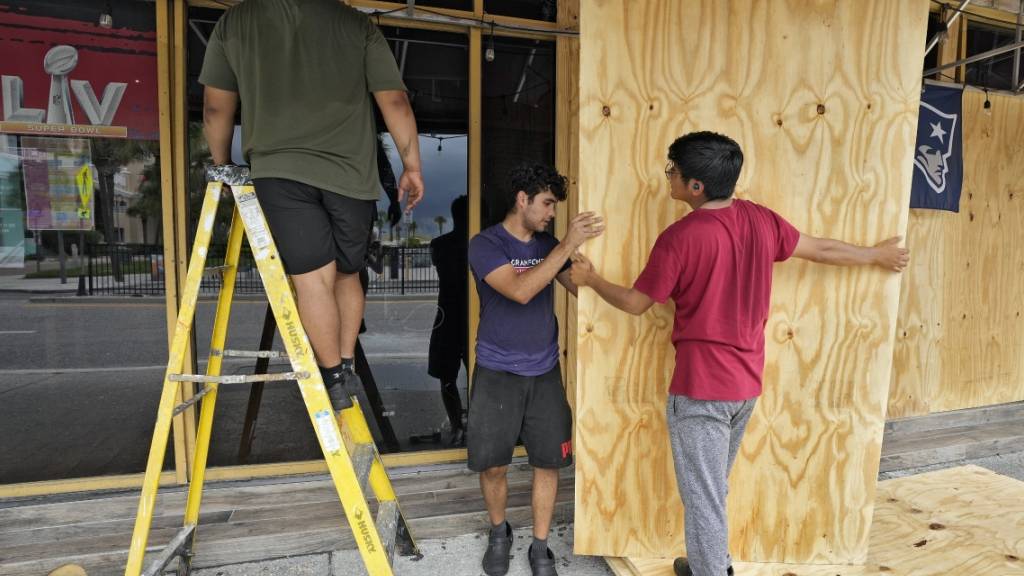 Männer verbarrikadieren in Tampa die Fenster eines Restaurants. «Idalia» könnte als Hurrikan der Kategorie drei auf die Westküste des US-Bundesstaates Florida treffen. Foto: Chris O'Meara/AP/dpa