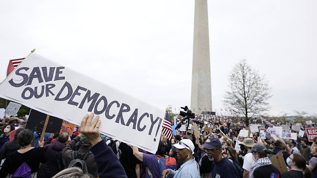 Demonstranten halten Schilder während einer «Hände weg!»-Demonstration gegen US-Präsident Trump am Washington Monument. Foto: Jose Luis Magana/AP/dpa