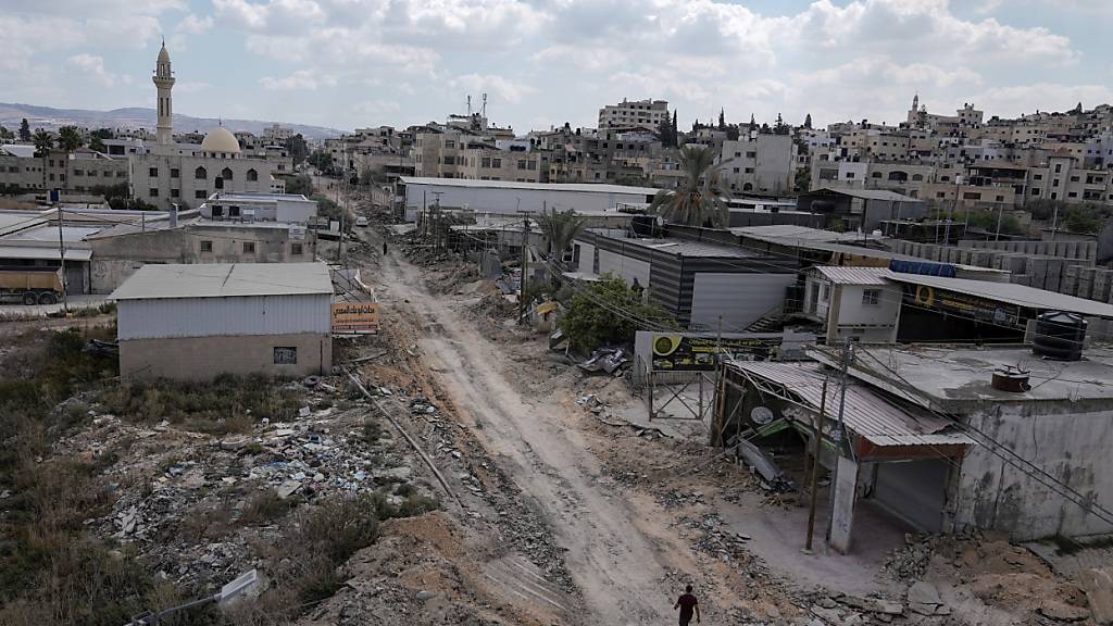 Ein Mann geht auf einer beschädigten Straße nach einer Razzia der israelischen Armee in Dschenin. Foto: Majdi Mohammed/AP/dpa