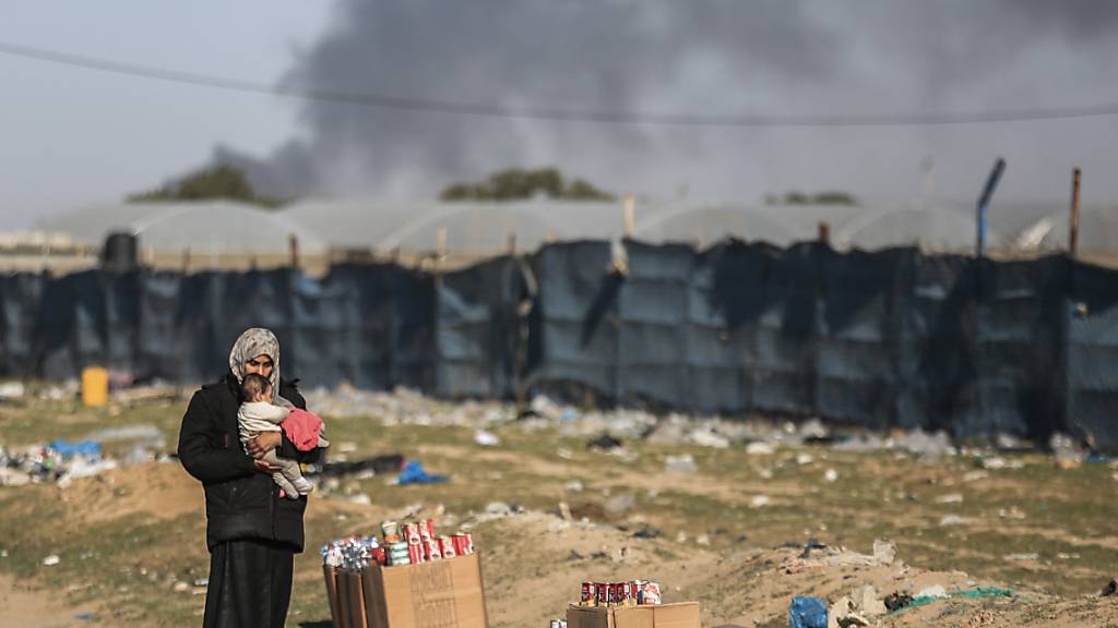 Eine Frau hält ein Kleinkind, während palästinensische Familien aus Chan Junis aufgrund israelischer Angriffe nach Rafah fliehen. Foto: Mohammed Talatene/dpa