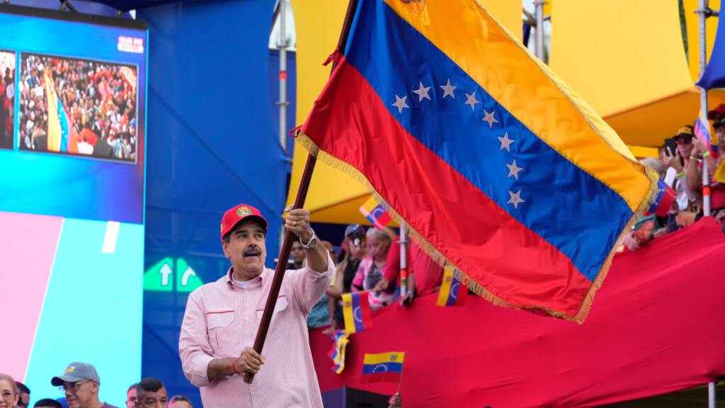 Der venezolanische Präsident Nicolas Maduro schwenkt eine venezolanische Flagge während einer Vereidigungsveranstaltung für von der Regierung organisierte Gemeinschaftskomitees im Präsidentenpalast. Foto: Ariana Cubillos/AP/dpa