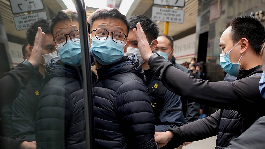 dpatopbilder - Der Herausgeber von «Stand News» Patrick Lam (l) wird von Polizeibeamten in einen Lieferwagen eskortiert. Mehrere Journalisten und ehemalige Mitarbeiter des pro-demokratischen Mediums wurden in Hongkong festgenommen. Foto: Vincent Yu/AP/dpa