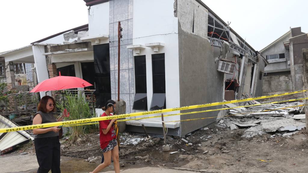 dpatopbilder - Zwei Frauen gehen nach einem starken Erdbeben in Davao City im Süden der Philippinen an einem beschädigten Haus vorbei. Foto: Manman Dejeto/AP/dpa