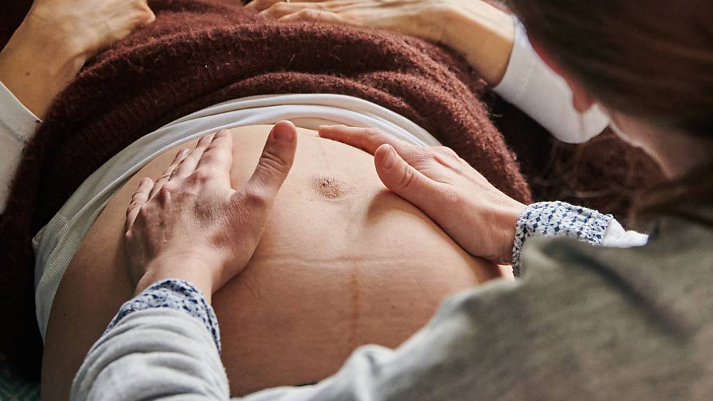 ARCHIV - Eine Hebamme tastet in ihrer Praxis den Bauch einer schwangeren Frau ab. Foto: Annette Riedl/dpa