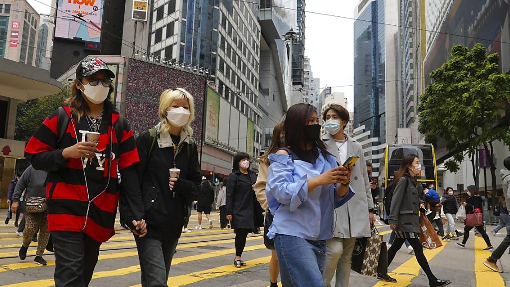 Menschen mit Masken gehen durch eine Straße in einem Hongkonger Einkaufsviertel. Foto: Vincent Yu/AP/dpa