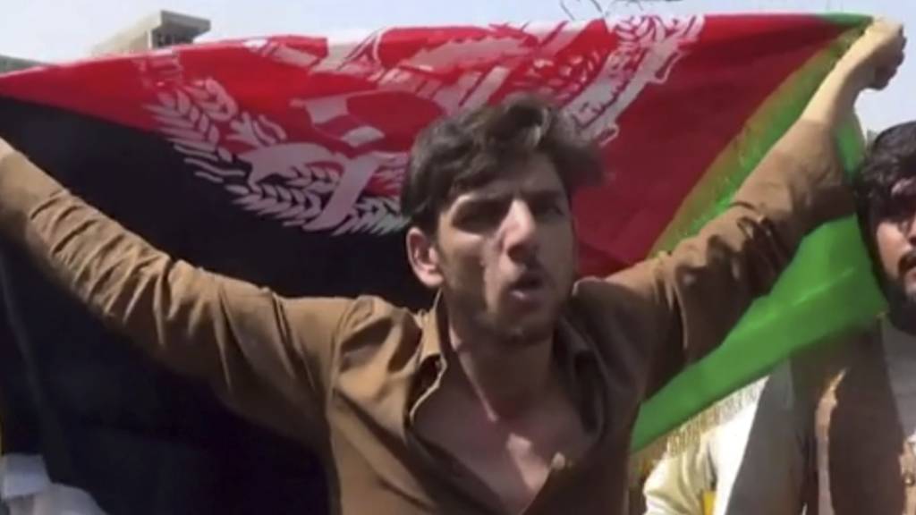 Ein Mann hält die Flagge Afghanistans während einer Demonstration in Jalalabad. Laut Videos in sozialen Medien finden in Afghanistan offenbar trotz des Siegeszugs der militant-islamischen Taliban weiter Demonstrationen mit der Nationalflagge statt. Foto: Uncredited/AP/dpa