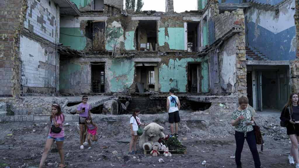 Menschen betrachten ein durch einen russischen Angriff zerstörtes Haus. Foto: Evgeniy Maloletka/AP/dpa