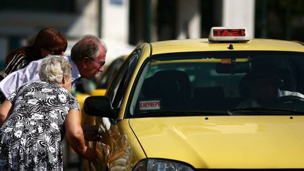 Ein älteres Paar sucht in Athen nach einem leeren Taxi. In der griechischen Hauptstadt und in Thessaloniki sind die Taxifahrer am Mittwoch in einen 24-stündigen Streik getreten. (Archiv)
