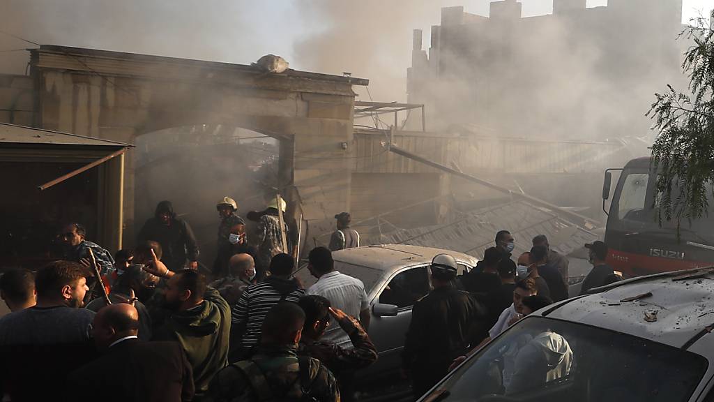 Sicherheitsbeamte und Rettungskräfte versammeln sich vor einem zerstörten Gebäude in Damskus, das bei einem israelischen Luftangriff getroffen wurde. Foto: Omar Sanadiki/AP/dpa