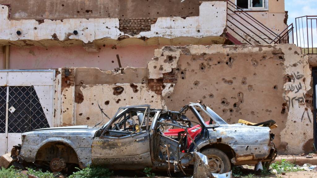 ARCHIV - ARCHIV. Ein zerstörtes Auto steht vor einem Haus voller Einschüsse. Jetzt sind zahlreiche Zivilisten bei einem Drohnenangriff auf einen Marktplatz ums Leben gekommen. Foto: Mudathir Hameed/dpa/Archivbild