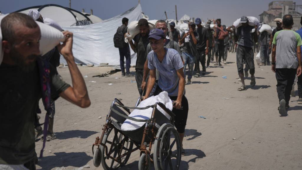 ARCHIV - Palästinenser tragen Mehlsäcke, die von einem humanitären Hilfskonvoi abgeladen wurden (Archivbild). Foto: Abdel Kareem Hana/AP/dpa