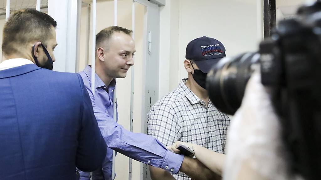 Iwan Safronow steht in einem Gerichtssaal in Moskau hinter Gittern und schüttelt einem Unterstützer die Hand. Foto: Sofia Sandurskaya/Moscow News Agency/AP/dpa