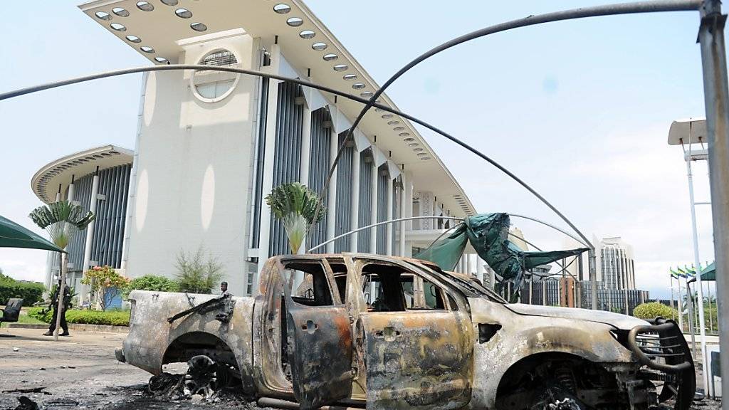 Ein ausgebranntes Auto vor einem Regierungsgebäude in Gabuns Hauptstadt Libreville.