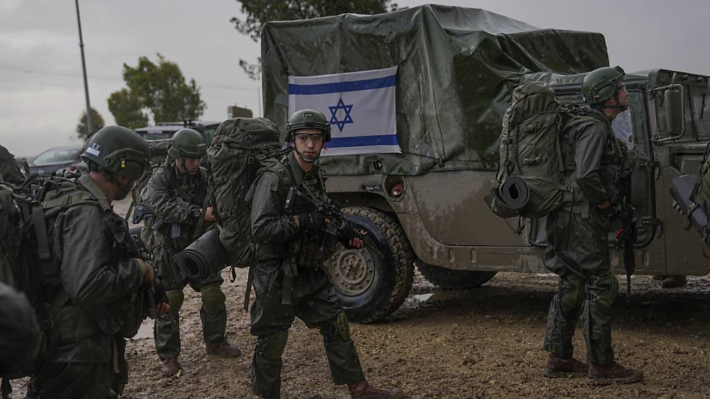 Israelische Soldaten stehen neben Militärfahrzeugen während sie sich an einem Sammelpunkt nahe der Grenze zum Gazastreifen vorbereiten. Foto: Ohad Zwigenberg/AP/dpa