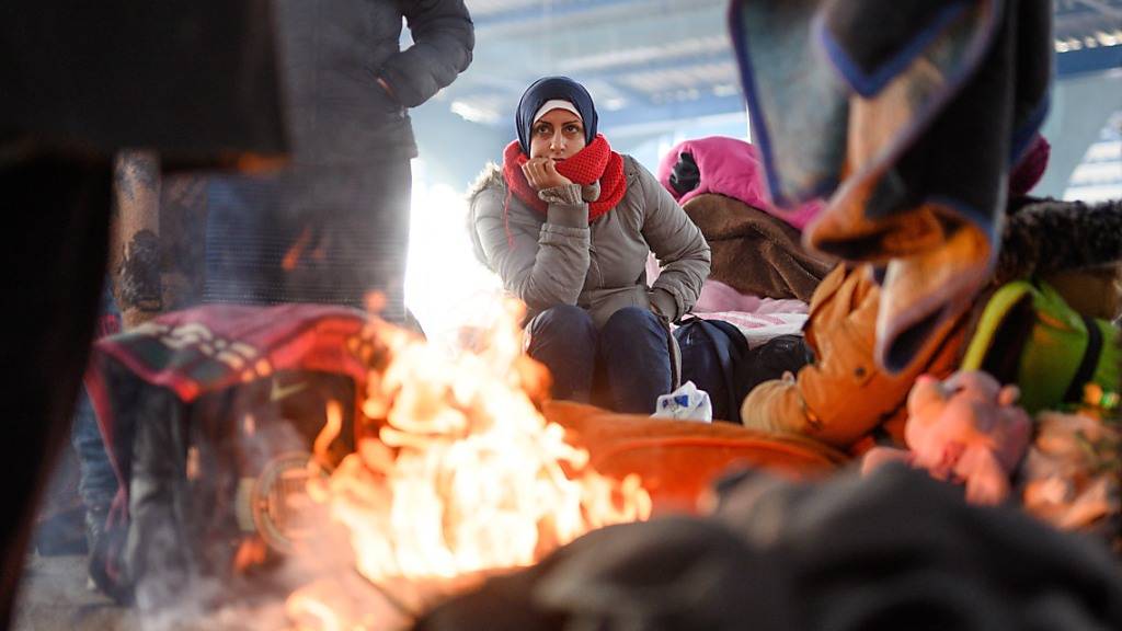 ARCHIV - Eine Frau aus Syrien sitzt an einem Lagerfeuer in einer leeren Markthalle nahe der türkisch-griechischen Grenze. Foto: Mohssen Assanimoghaddam/dpa