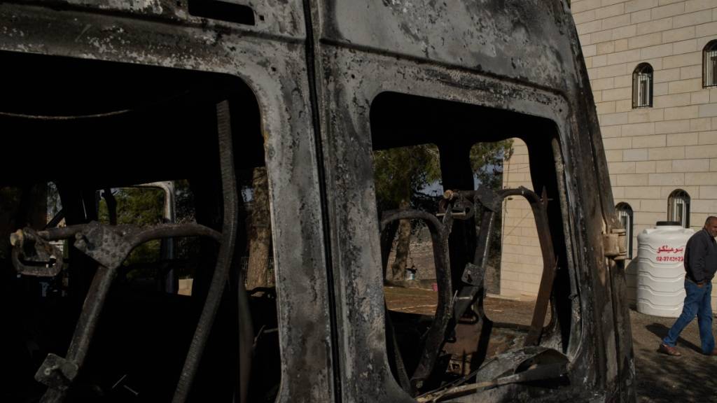 ARCHIV - Moussab Mshala geht an einem Fahrzeug vorbei, das bei einem Angriff israelischer Siedler vor seinem Haus im Westjordanlanddorf al-Jab'a in der Nähe von Bethlehem verbrannt ist. Foto: Leo Correa/AP/dpa