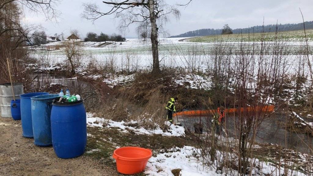 Feuerwehrangehörige errichten eine Ölsperre in der Bünz.