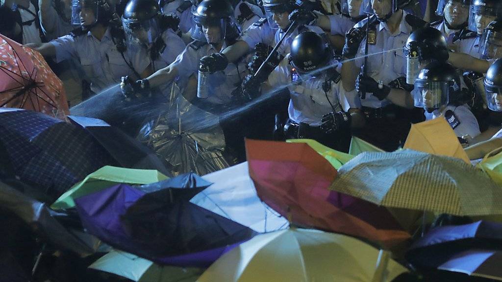 Mit Regenschirmen schützen sich Demonstranten in Hongkong vor Pfefferspray von Polizisten.