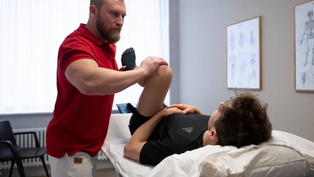 Die Branche «Gesundheits- und Sozialwesen» beschäftigte im 2024 die meisten Erwerbstätigen: Ein Therapeut bewegt das Knie eines Patienten im Behandlungsraum (Symbolbild).