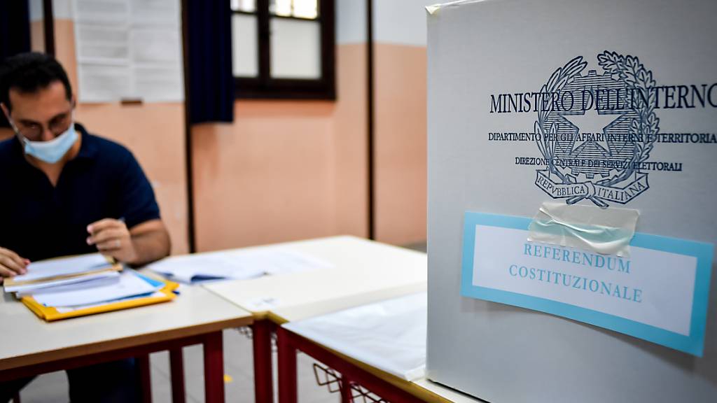 Ein Wahlhelfer sitzt an einem Tisch neben in der Parini-Mittelschule neben einer Wahlurne. Foto: Claudio Furlan/LaPresse via ZUMA Press/dpa