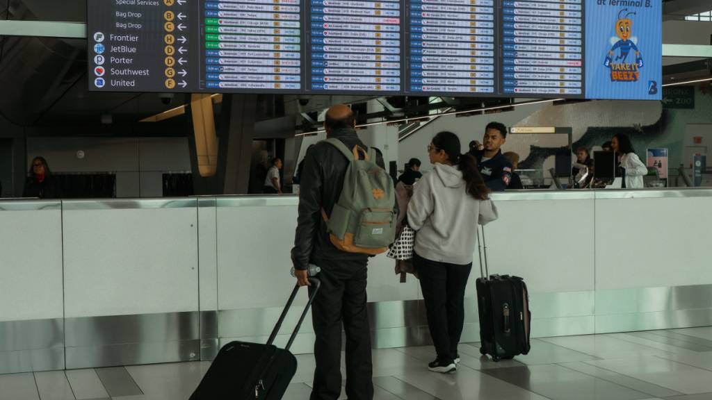 dpatopbilder - Reisende prüfen den Flugplan am LaGuardia International Airport in New York. Foto: Olga Fedorova/FR172242 AP/AP/dpa