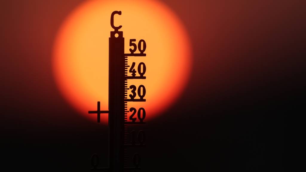ARCHIV - Hinter einem Thermometer geht am Morgen die Sonne auf. Foto: Thomas Warnack/dpa
