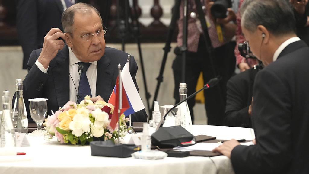 Sergej Lawrow (l), Außenminister von Russland, richtet seinen Kopfhörer. Foto: Tatan Syuflana/AP/dpa