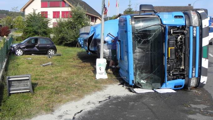 Lastwagen kippt und beschädigt Auto