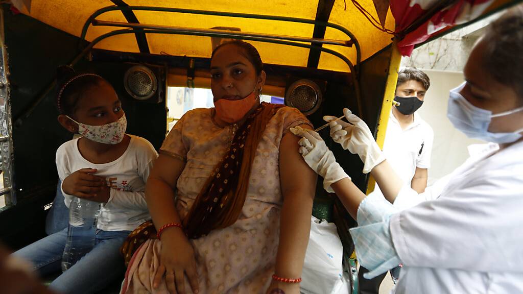 Eine Mitarbeiterin des Gesundheitswesens impft in Ahmedabad eine Frau gegen das Coronavirus.