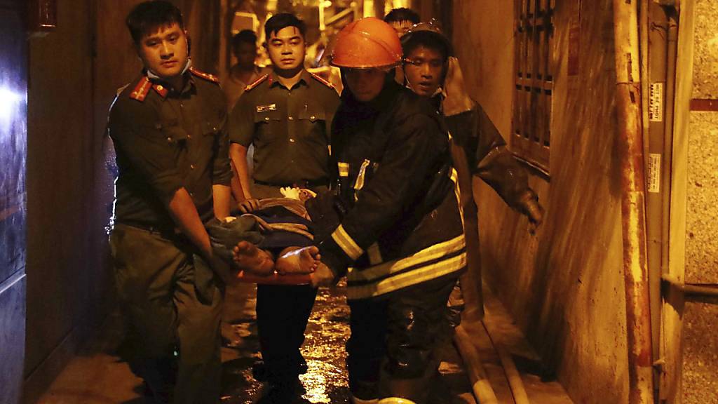 Rettungskräfte tragen eine verletzte Person auf einer Trage aus einem brennenden Gebäude. Foto: Pham Trung Kien/VNA/AP/dpa