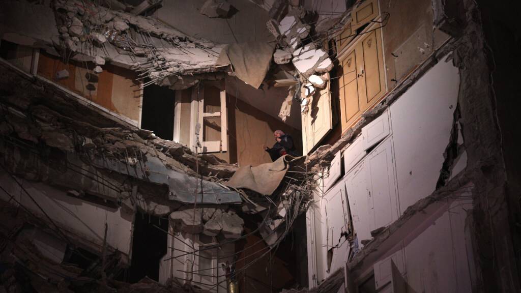 ARCHIV - Eine Frau, die einen israelischen Luftangriff überlebt hat, wartet darauf, aus einem zerstörten Gebäude im Zentrum von Beirut gerettet zu werden. Foto: Emilio Morenatti/AP/dpa